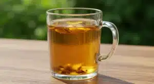 Natural Zepbound recipe drink steeping in a clear glass mug on a rustic wooden table with golden glow.